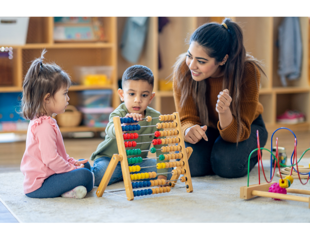 woman in brown blouse on floor with children playing with wooden toys